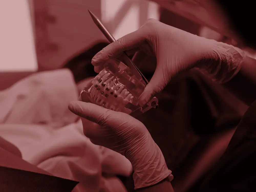 Gloved hands checking a clear dental model