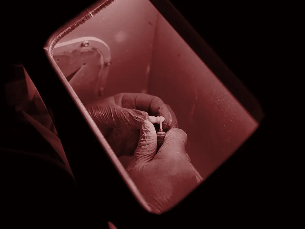 Dental technician working under a curing light in the laboratory