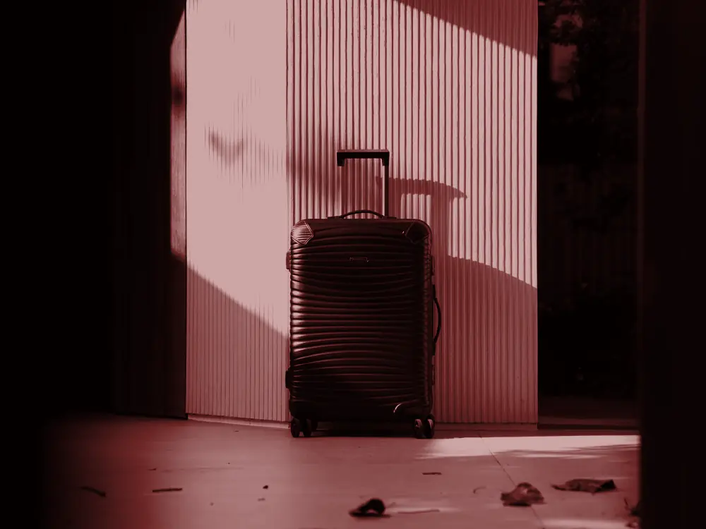Suitcase standing in a sunlit doorway